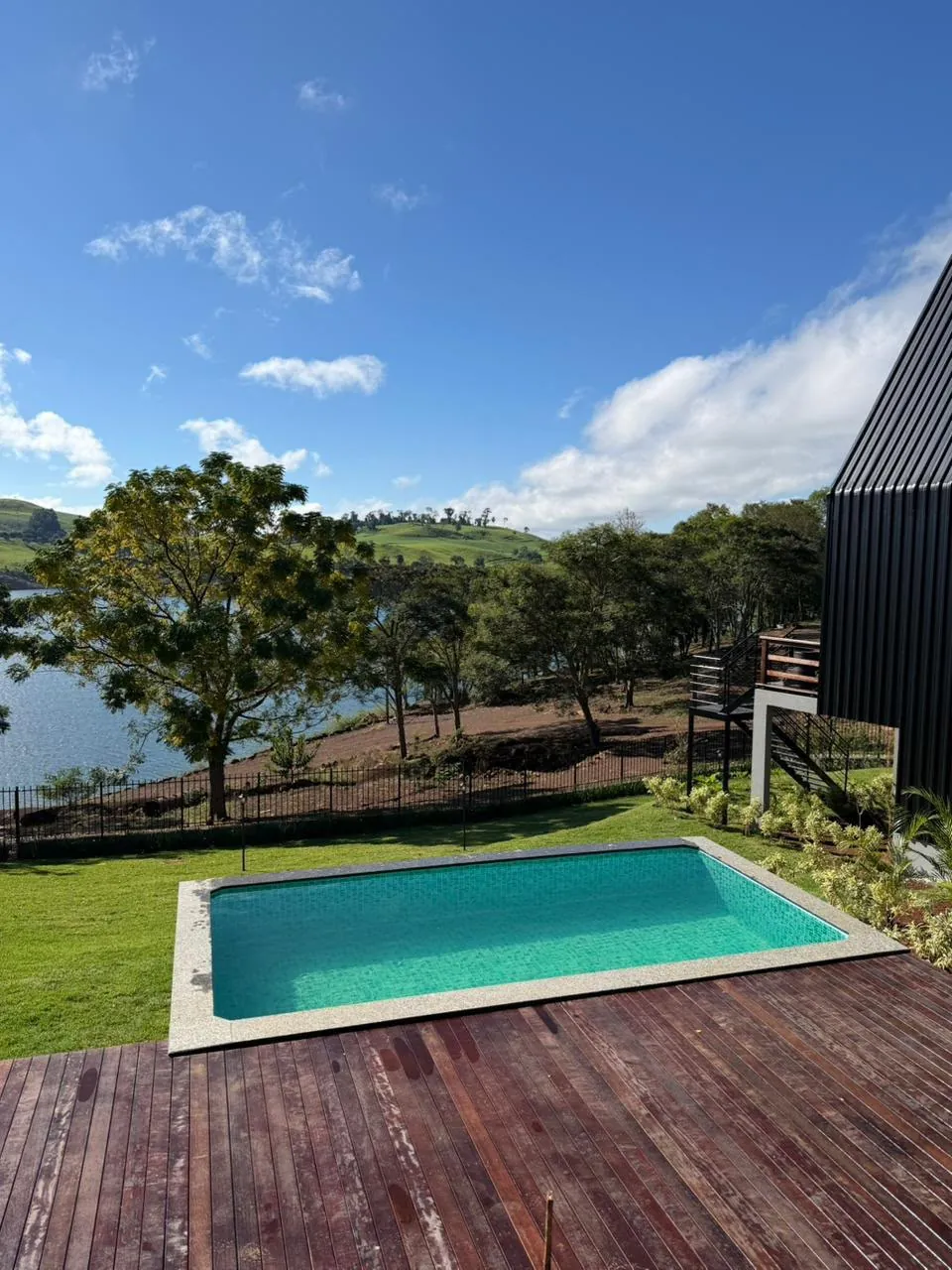Piscina com deck de madeira e vista para o lago